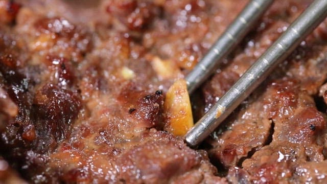 Lifting garlic pieces in tteokgalbi with chopsticks