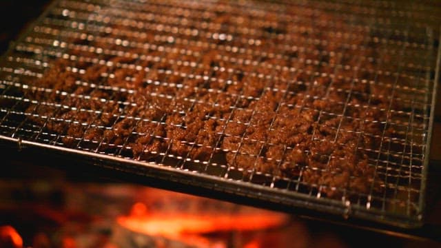Grilled bulgogit sizzling over hot charcoal at a barbecue