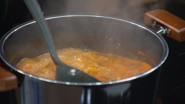Hands serving a bowl of boiling soup