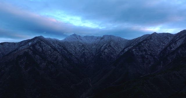 Snow-covered mountains under cloudy skies