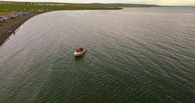 Boat on a lake with a campsite nearby