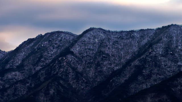 Snow-covered mountains under cloudy skies