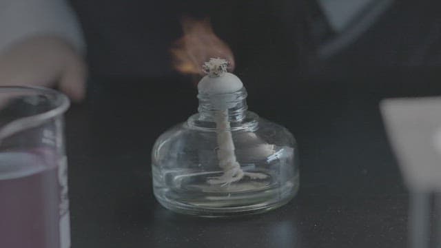 Student conducting experiments with alcohol lamp in lab