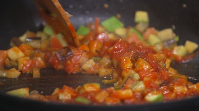 Stir-frying tomato sauce and vegetables in a frying pan