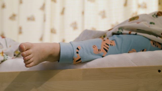Child Lying on a Cozy Bed and Wiggling His Foot