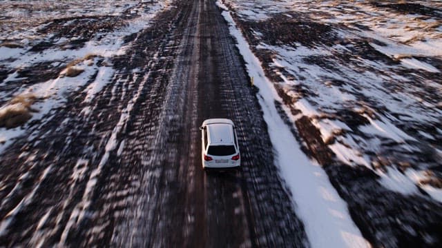 Car driving on a snowy road in a vast landscape