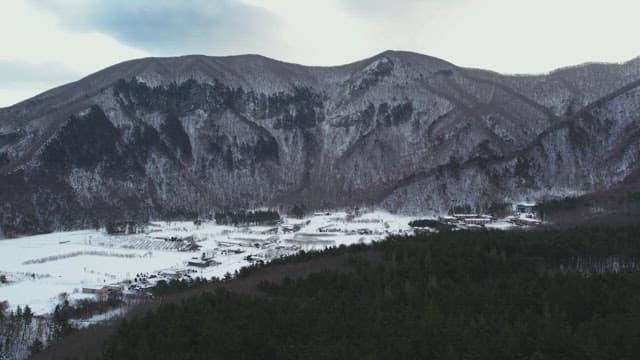 Snow-Covered Village Under Lush Snowy Mountains