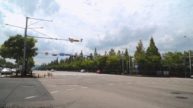 Urban intersection under a cloudy sky with moving vehicles.