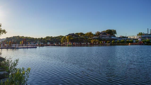 Riverside of Jinjuseong Fortress scenery with trees and colorful lanterns on a sunny day