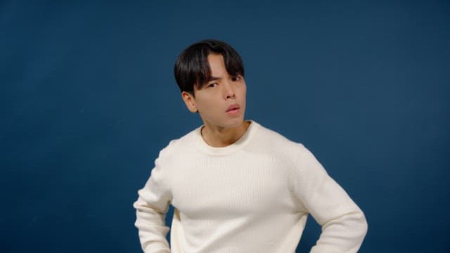 Man in a white sweater looking straight ahead with a puzzled expression