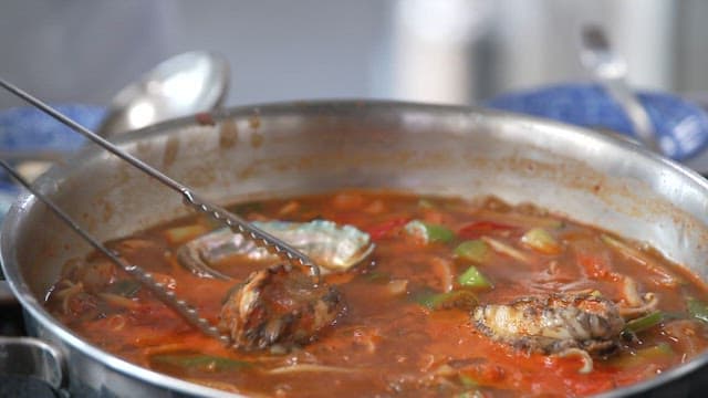 Close-up of a simmering pot of spicy stew with vegetables and abalone