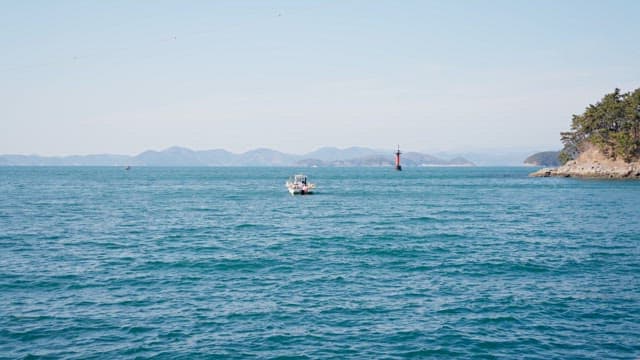 Small boat on a calm sea with distant mountains