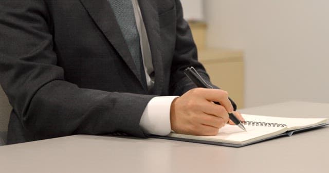 Office Worker Wearing a Suit and Taking Notes in a Diary