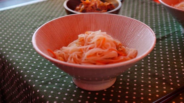 Close-up of noodles being prepared in a bowl.
