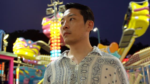 Man in a colorful amusement park at night