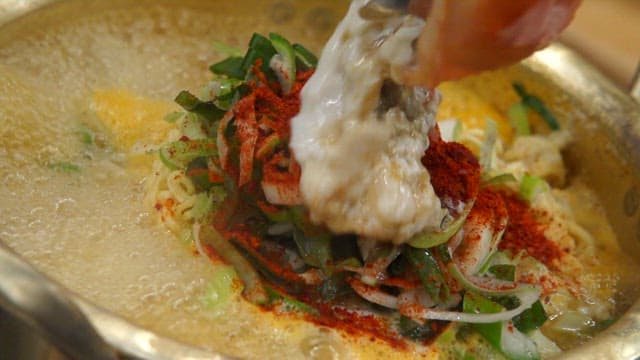 Crab innards added to the ramen boiling in a pot