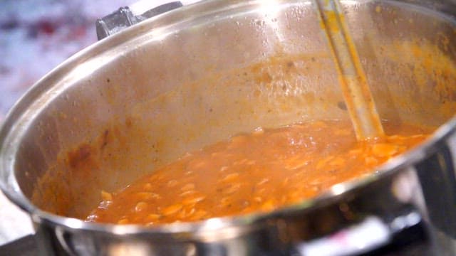 Ladleful of rose sauce boiling in a pot