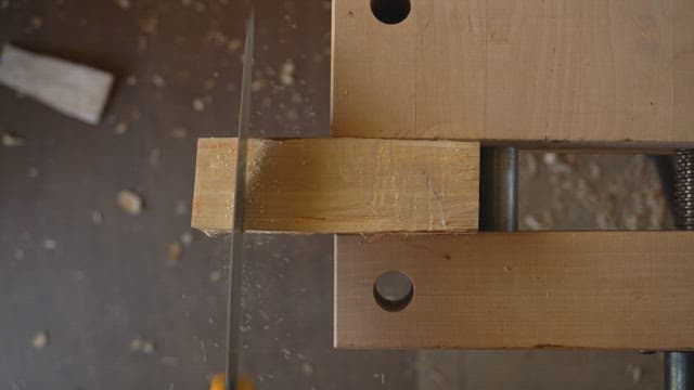 Wood being cut with a saw on a workbench