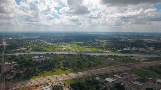 Wide town landscape with highways and green spaces under a cloudy sky