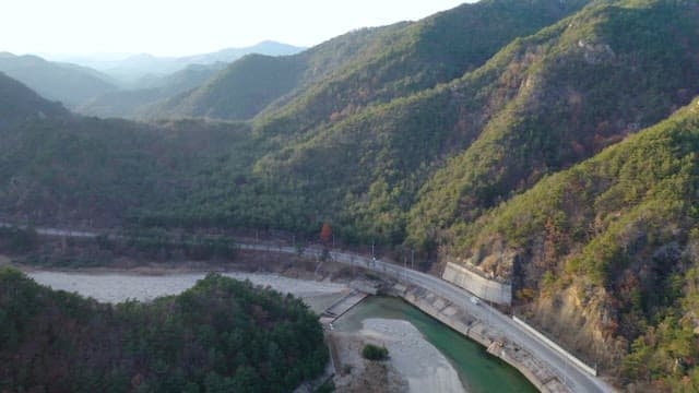 Road Between a Lush Mountainside and a Quiet River