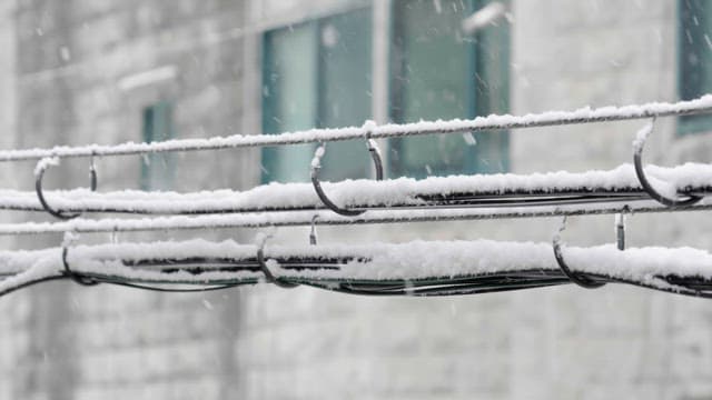 Snow falling on wires in front of a building