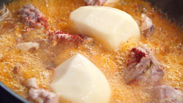 Spicy seasoned chicken and potatoes boiling in a pot