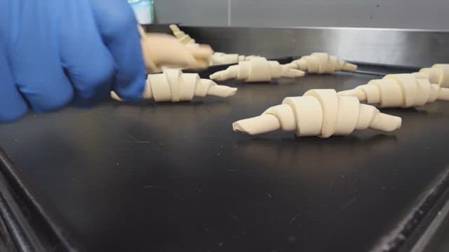 Placing croissant dough on a baking tray in an industrial kitchen