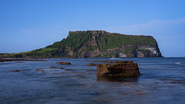 Seongsan Ilchulbong with Lush Greenery and Serene Sea on a Sunny Day