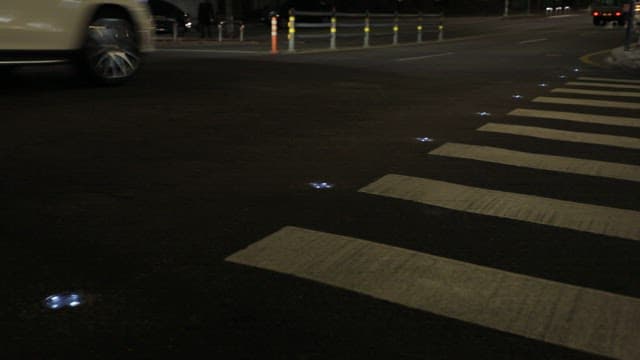 Crosswalk on a Road with Guiding Lights on at Night