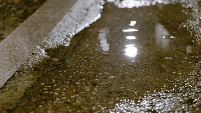 Rain puddle reflecting streetlights at dark night