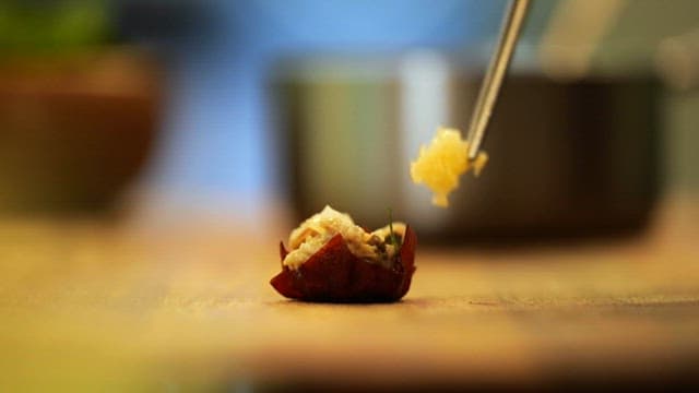 Delicate dessert being garnished with precision in a kitchen