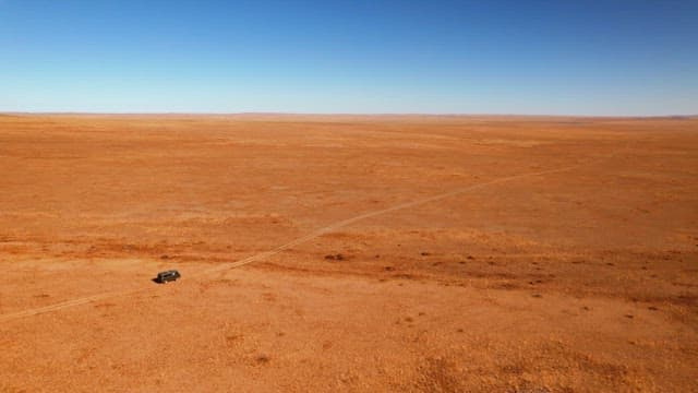 Solitary Vehicle Traversing Vast Desert Landscape