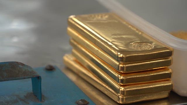 Stack of gold bars on a metal surface