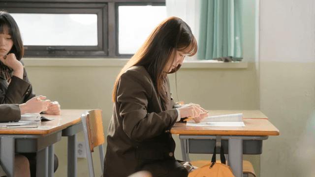 Student sharpening a pencil with a knife on a book