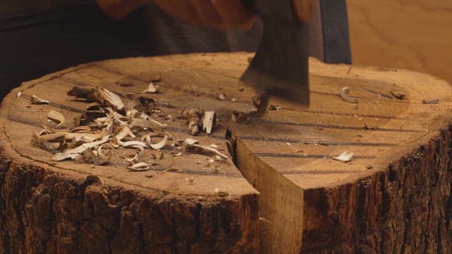 Person carving wood with an ax
