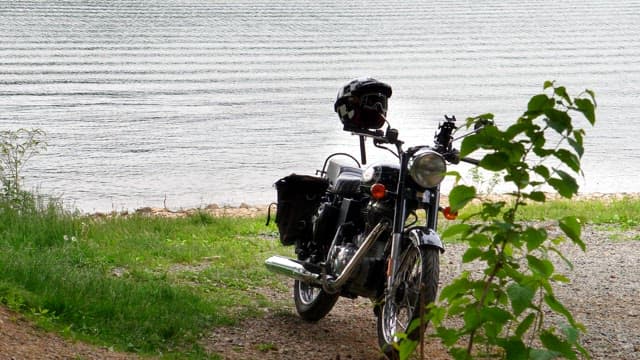 Black motorcycle parked on a grassy lakeside