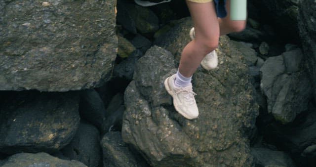 Feet Carefully Stepping on Steep Rocks