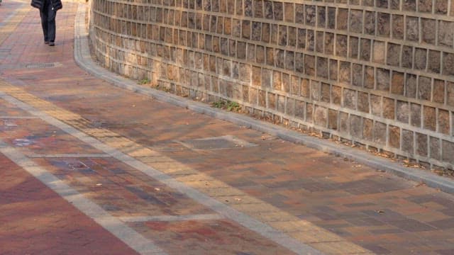 People walking along a brick wall path