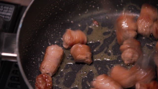 Sausages being cooked in a frying pan