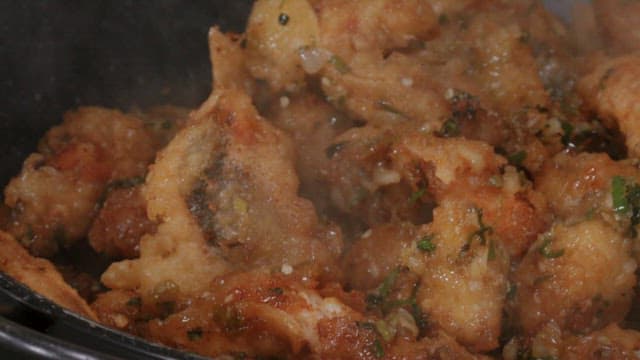 Fried fish with seasoning and vegetables stir-fried in a frying pan
