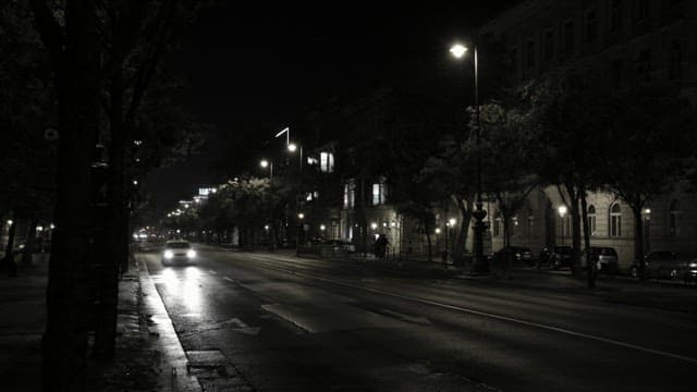 Nighttime City Street with Passing Cars and Illuminated Building