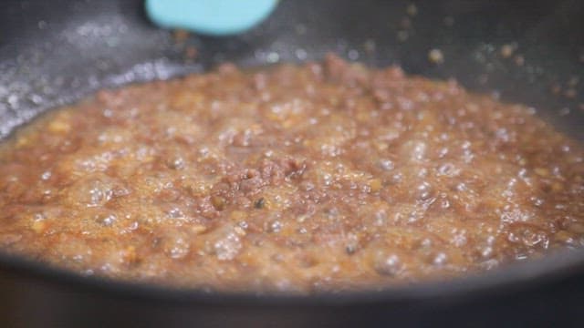 Stir-frying beef and sauce in a frying pan