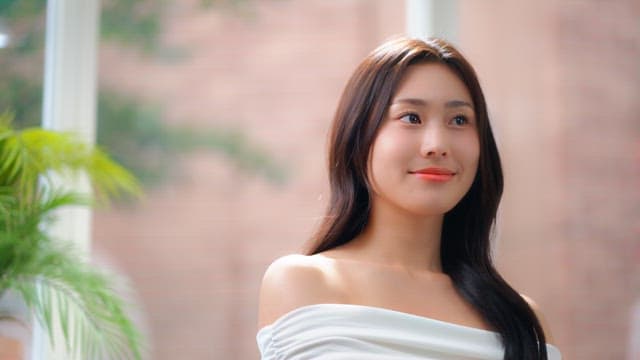 Woman's face smiling brightly in a room with sunlight through the window