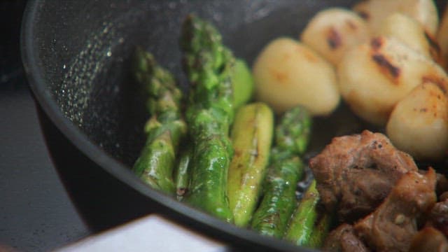 Asparagus, skirt meat and garlic cooking in a pan