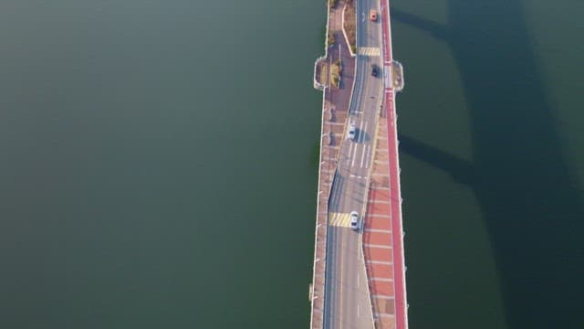 Cars driving on a bridge over a calm river