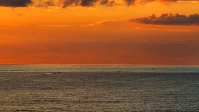 Serene ocean at sunset with orange sky