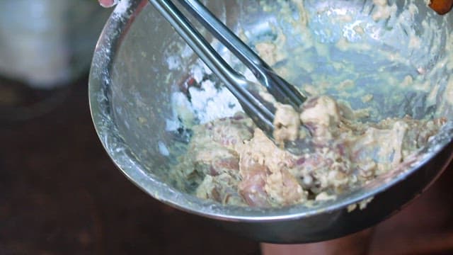 Frying the battered chicken in hot oil in a pan