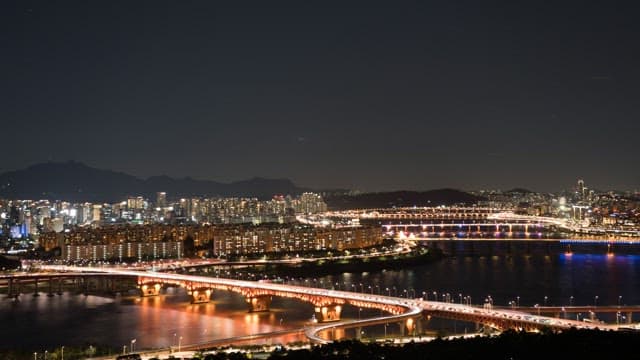 Illuminated Riverside Cityscape and Bridge at Night