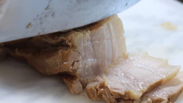 Chef slicing boiled pork in a restaurant kitchen