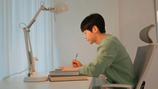 Man writing at a desk in a calmly lit room